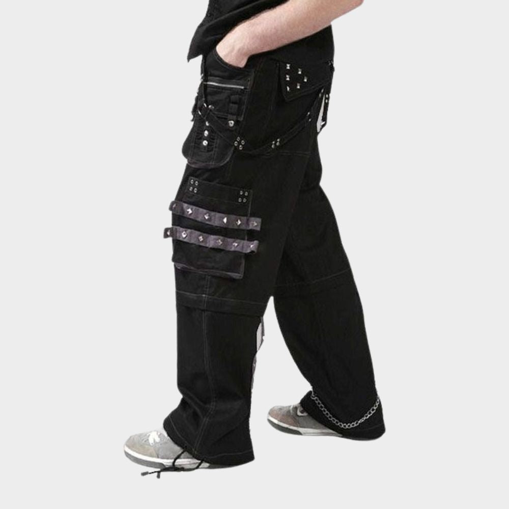 Model wearing black emo cargo pants made from 100% cotton, featuring multiple pockets and a gothic design with studs and metal accents.