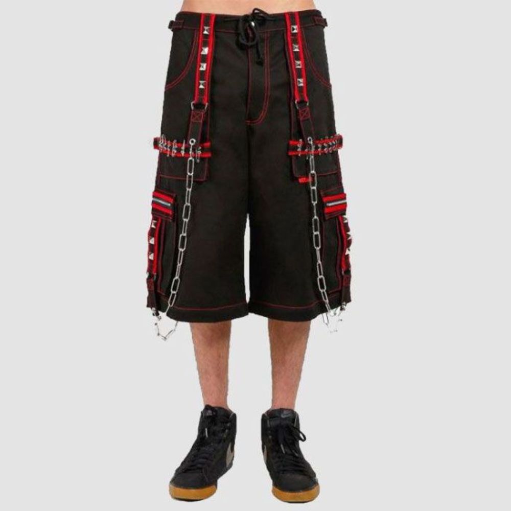 Close-up of black Tripp NYC cargo pants with red accents, showcasing safety pins, removable chains, and D-rings for a punk rock aesthetic.